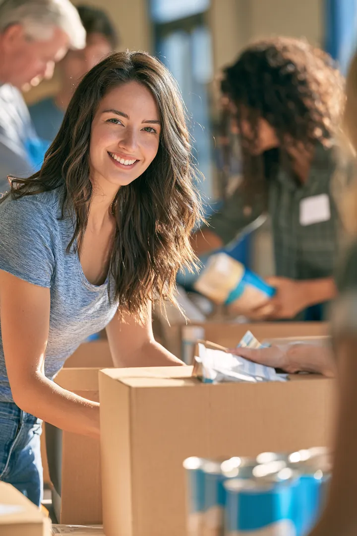 Volunteers of mixed ages stacking food boxes in a bright community center, a reminder that personal loan budgets support real households